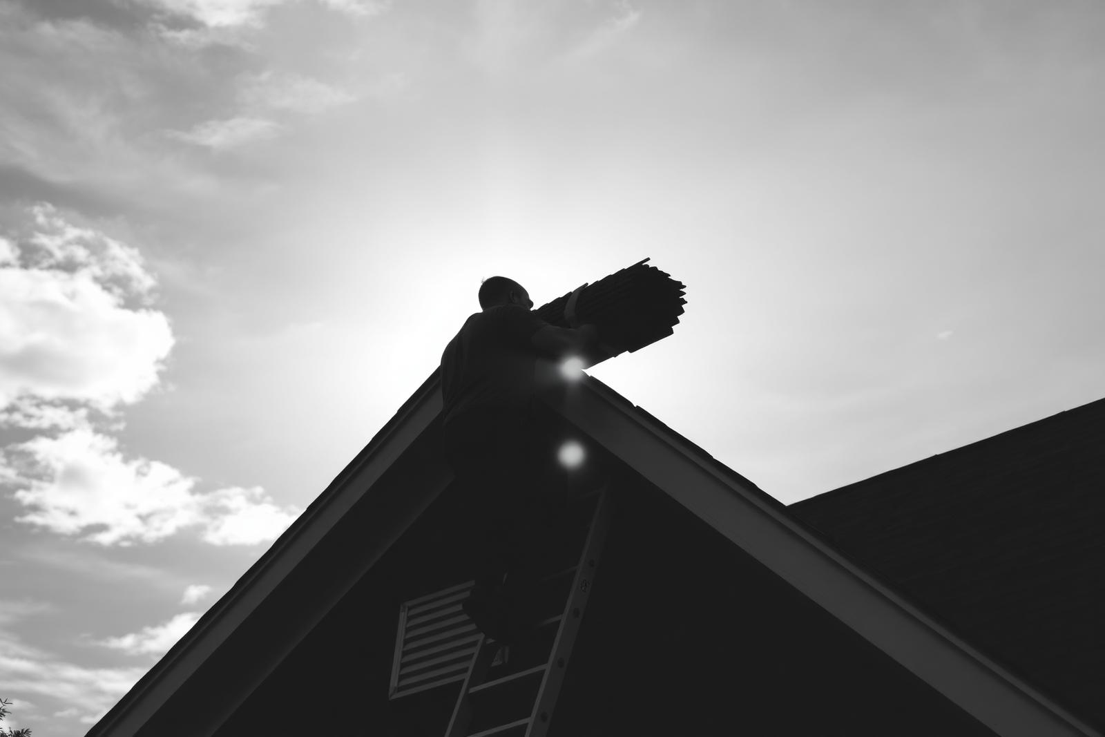 Roofer carrying shingles up a ladder